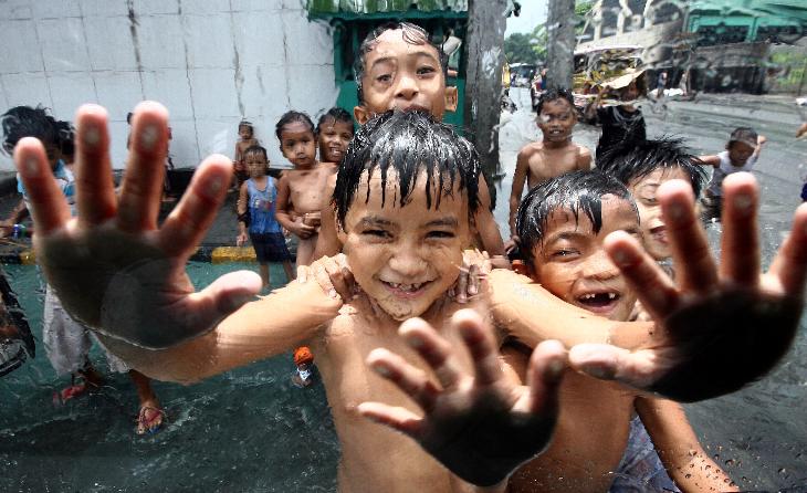 Children enjoy playing in the rain after a sudden downpour occurred in Quezon city, Philippines.